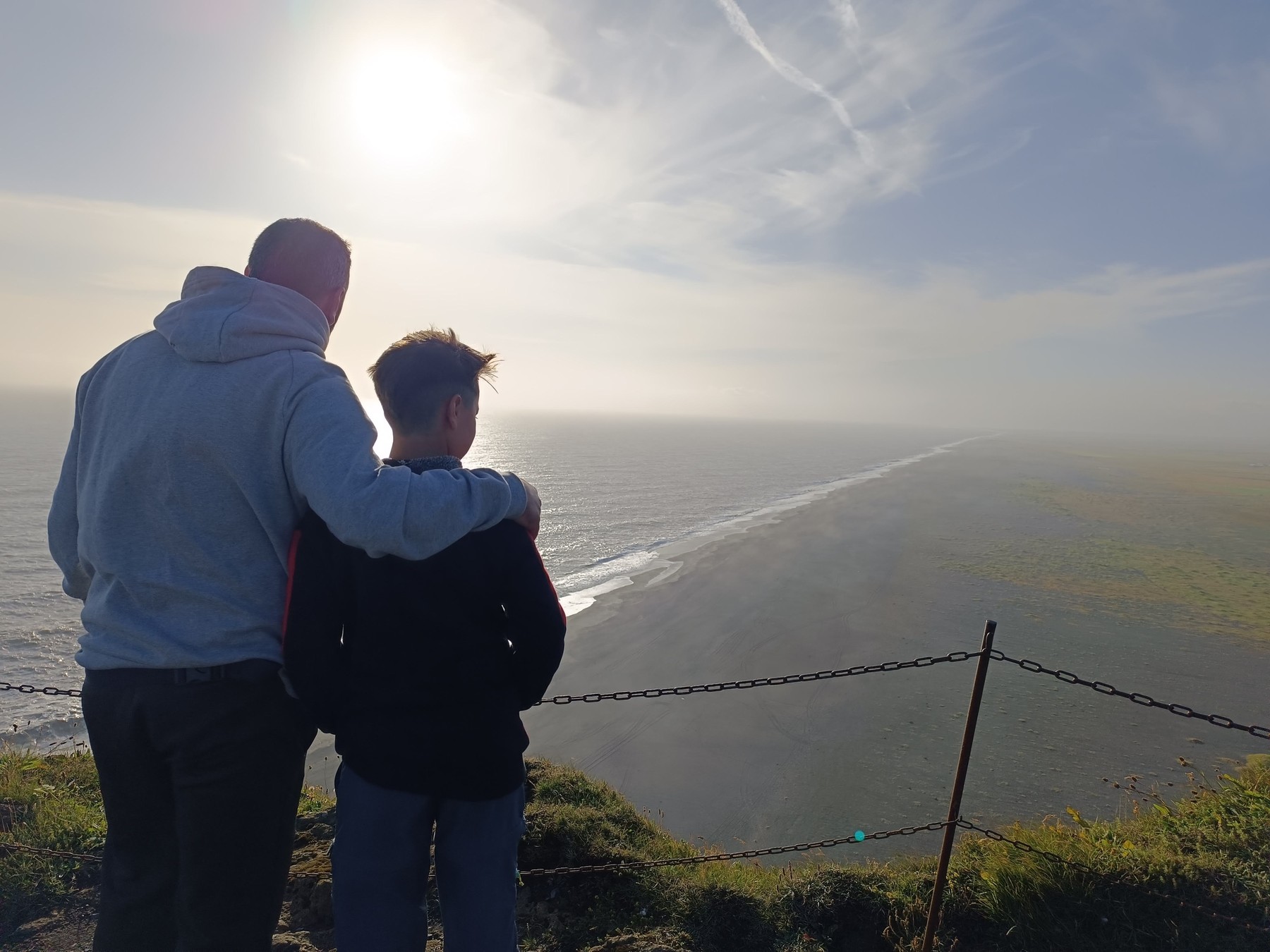 Enrique con su hijo, de espaldas, mirando el mar desde un mirador